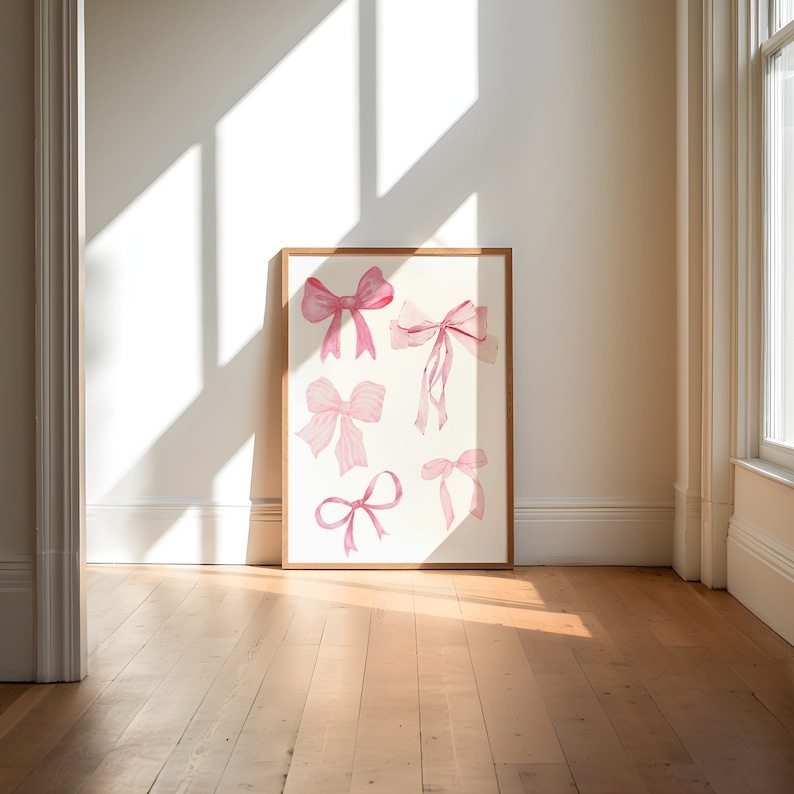 May include: A framed print of six pink watercolor bows on a white background. The bows are arranged in a vertical column, with the largest bow at the top and the smallest bow at the bottom.