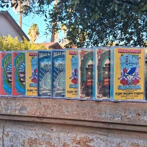 May include: A row of nine cassette tapes featuring Dead & Company concert artwork. The covers display colorful illustrations of the Golden Gate Bridge, cable cars, and skulls with text reading Dead & Company Golden Gate Park August 1, 2, 3, 2025.