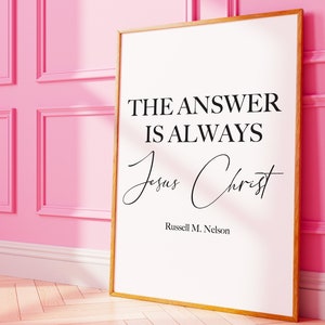 May include: A white framed print with a black quote that reads "The answer is always Jesus Christ" by Russell M. Nelson.