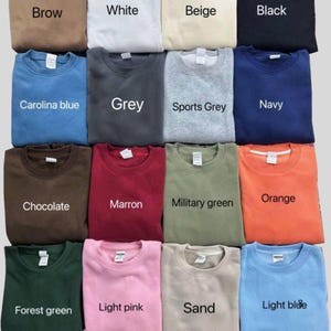 May include: A collection of folded crewneck sweatshirts in various colors, including Carolina blue, grey, and orange. Each sweatshirt displays a color name, such as "Brow", "White", and "Black". The sweatshirts are neatly arranged, showcasing a range of hues.