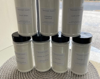 May include: Six white plastic jars with black lids containing homemade carpet freshener. The jars are labeled with the scent names: Fruit Slices, Mahogany Teakwood, Lush Linen, Clean Cotton, Lavender & Vanilla, My Man, and Midnight Ice.