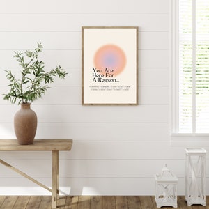 Op de afbeelding: Een ingelijst print met een perzik- en blauwe gradi&euml;ntcirkel en de tekst "You Are Here For A Reason..." in zwart. De tekst gaat verder met een lijst van redenen om hier te zijn, waaronder "to understand", "to experience", "to learn", "to love", "to teach", "to help", "to choose", "to create", "to believe", "to connect", "to change" en "to inspire".