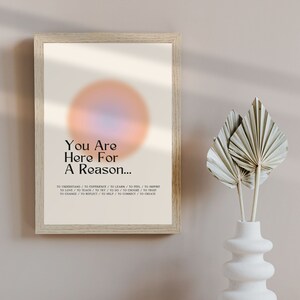 Op de afbeelding: Een motiverende poster met een perzikkleurige cirkel en de tekst "You Are Here For A Reason..." gevolgd door een lijst met werkwoorden: "To Understand / To Experience / To Learn / To Feel / To Inspire / To Love / To Teach / To Try / To Do / To Choose / To Trust / To Change / To Reflect / To Help / To Connect / To Create."