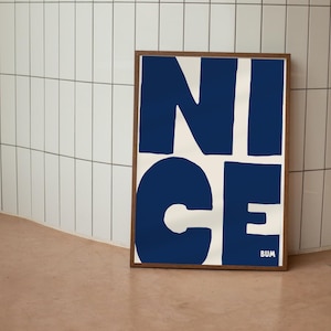 Può includere: Una stampa incorniciata con la parola "NICE" in grandi lettere blu e in grassetto su uno sfondo bianco. La parola "BUM" è stampata in lettere piccole nell'angolo in basso a destra.
