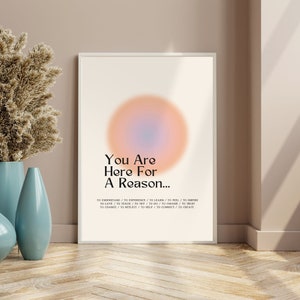 Op de afbeelding: Een motiverende poster met een licht oranje en blauwe gradi&euml;ntcirkel in het midden. De tekst luidt "You Are Here For A Reason..." en somt een reeks werkwoorden op: "To understand, to experience, to learn, to feel, to inspire, to love, to teach, to try, to do, to choose, to trust, to change, to reflect, to help, to connect, to create."