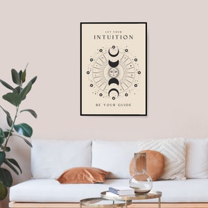 May include: A black and white poster with a circular design featuring a sun and moon phases. The text "Let your intuition be your guide" is printed on the poster.