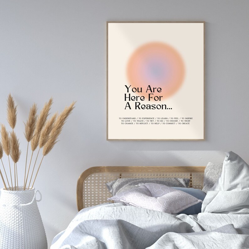 Op de afbeelding: Een motiverende poster met een wazige, perzikkleurige en blauwe cirkel in het midden. De tekst luidt "You Are Here For A Reason..." en somt een reeks werkwoorden op, waaronder "to understand", "to experience", "to learn", "to feel", "to inspire", "to love", "to teach", "to try", "to do", "to choose", "to trust", "to change", "to reflect", "to help", "to connect" en "to create".