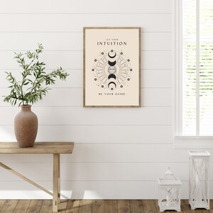May include: A beige poster with a black and white illustration of a sun and moon with the text "Let your intuition be your guide".