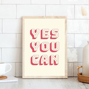 Może przedstawiać: Wydruk w ramie z kremowym tłem i tekstem "YES YOU CAN" w pogrubionych, czerwonych literach z białym obramowaniem.