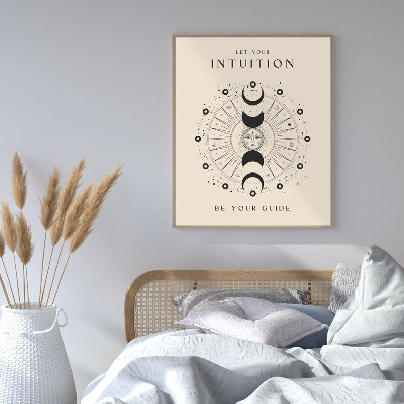 May include: A beige poster with black text and a black and white illustration of a sun and moon phases. The text reads "Let your intuition be your guide".