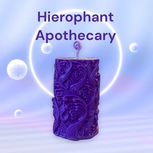 May include: Purple candle with a swirling, ornate design. The candle is tall and cylindrical, with a wick sticking out of the top. The candle is set against a light blue background.