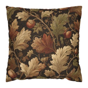 May include: Square cushion with a botanical design. The cushion features a dark brown background with a repeating pattern of oak leaves and acorns in shades of beige, green, and rust. The design has a vintage, artistic style.