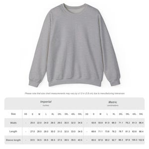 May include: A heather gray sweatshirt with a crew neck. The size chart below the sweatshirt shows measurements in inches and centimeters. The width of the sweatshirt ranges from 20.0 to 34.0 inches.