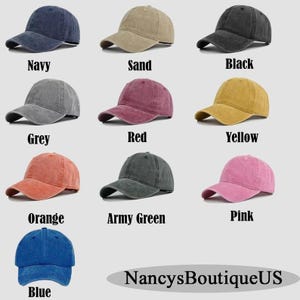 Op de afbeelding: Een verzameling van negen baseballpetten in verschillende kleuren, waaronder marineblauw, zand, zwart, grijs, rood, geel, oranje, legergroen, roze en blauw. Elke pet heeft een gebogen klep en een klassiek zes-panelen ontwerp. De tekst "NancysBoutiqueUS" staat onderaan.
