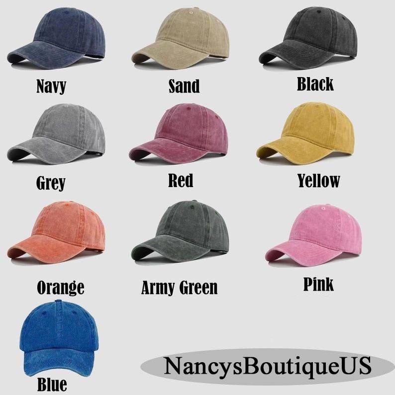 Op de afbeelding: Een verzameling van negen baseballpetten in verschillende kleuren, waaronder marineblauw, zand, zwart, grijs, rood, geel, oranje, legergroen, roze en blauw. Elke pet heeft een gebogen klep en een klassiek zes-panelen ontwerp. De tekst "NancysBoutiqueUS" staat onderaan.