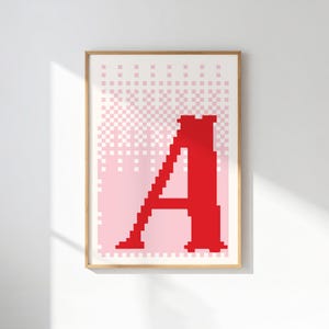 Könnte beinhalten: Gerahmter Druck mit einem großen roten Buchstaben "A" in Pixel-Optik. Der Hintergrund verläuft von Weiß zu Rosa mit einem Rastermuster. Das Kunstwerk wird in einem Holzrahmen präsentiert, ideal für die Wanddekoration.
