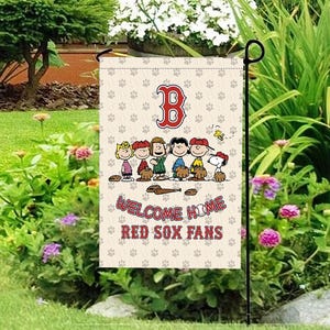 Könnte beinhalten: Eine Gartenflagge mit dem Logo der Boston Red Sox und Peanuts-Charakteren. Die Flagge hat einen beigen Hintergrund mit Pfotenabdrücken und dem Text "Welcome Home Red Sox Fans". Die Flagge wird in einem Garten gezeigt.