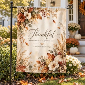 May include: A rectangular garden flag featuring a cream-colored background with autumn-themed floral arrangements of orange, brown, and white flowers, leaves, and wheat. The text reads Thankful, grateful hearts gather here, and Autumn blessings.