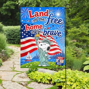 Może przedstawiać: Niebieska flaga ogrodowa z napisem "Land of the free, home of the brave" i kreskówką Snoopy'ego jako Statua Wolności. Flaga zawiera również amerykańską flagę, fajerwerki i żaglówkę.