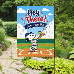 Könnte beinhalten: Eine Gartenflagge mit Snoopy beim Baseballspielen mit Woodstock. Die Flagge hat einen blauen Himmelshintergrund mit den Worten "Hey There! Come Hang Out" in Rot und Weiß. Baseball-Thema.