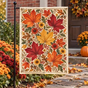 May include: A rectangular garden flag featuring a cream-colored background with a vibrant autumn pattern of large red, orange, and yellow maple leaves, small yellow flowers, clusters of red berries, and brown acorns on a black metal pole.