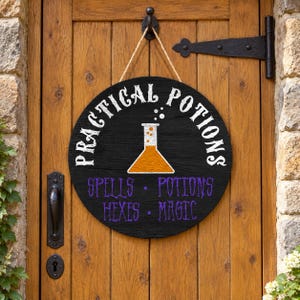May include: A round black wooden sign hanging by a jute rope. The sign features the white text "PRACTICAL POTIONS" arched above a central graphic of an orange liquid-filled flask. Below the flask, purple text reads "SPELLS • POTIONS HEXES • MAGIC".