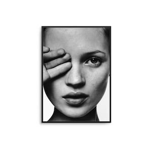 May include: Black and white framed portrait of a person with their hand covering one eye. The image is a close-up of the face, with a focus on the eye and facial features. The portrait is in a rectangular frame.