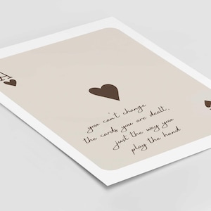 Op de afbeelding: Een beige kaart met een bruine aas van harten en de tekst "you can't change the cards you are dealt, just the way you play the hand".