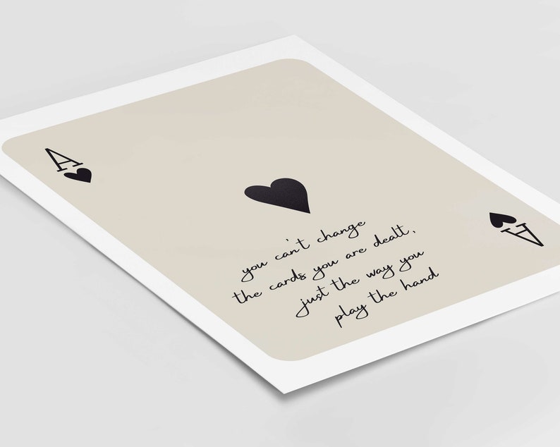 Op de afbeelding: Een beige achtergrond met een zwarte aas van harten speelkaart. De kaart heeft de tekst "you can't change the cards you are dealt, just the way you play the hand".