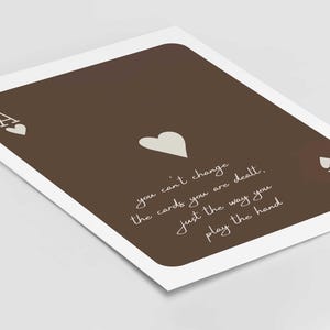 May include: A brown playing card print featuring the Ace of Hearts. The card has a white border and includes the text: "you can't change the cards you are dealt, just the way you play the hand."
