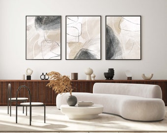 May include: Three abstract art prints in black frames with beige and gray abstract shapes and lines. The prints are hanging on a white wall above a white couch and a wooden shelf with decorative objects.