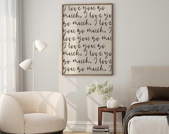 May include: A framed wall art piece with the text "I love you so much" in a handwritten style. The artwork is in a wooden frame and hangs above a bed. The room also features a cream-colored armchair, a floor lamp, and a small wooden side table.