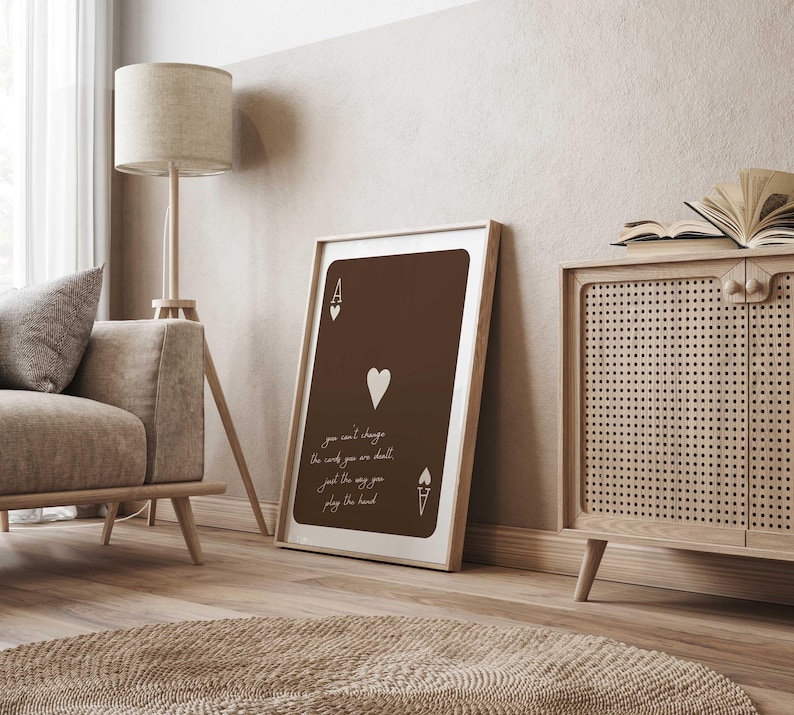 May include: A framed print of the Ace of Hearts playing card, in shades of brown and white. The card features the Ace symbol, a heart, and the text: "you can't change the words you are dealt, just the way you play the hand."