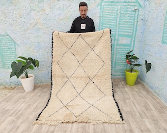 May include: A white and black Moroccan rug with a diamond pattern. The rug is hand-woven and has a soft, fluffy texture.