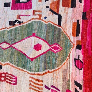 May include: A colorful rug with a geometric pattern in shades of pink, green, orange, and white. The rug has a diamond-shaped design in the center.