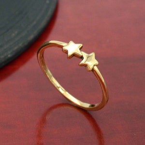 May include: A gold ring with two small star-shaped accents.