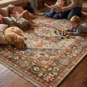 May include: A large rectangular area rug featuring a complex pattern with a central medallion in shades of rust orange, sage green, and deep blue. The rug has a wide decorative border with floral motifs and a fringed edge on the short sides.