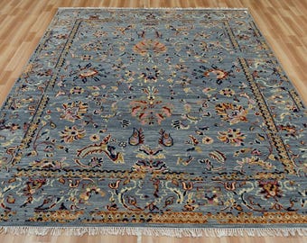 May include: A rectangular, blue area rug with an intricate floral pattern. The rug features a central medallion design and a detailed border. The color palette includes shades of blue, beige, and touches of orange and pink. The rug has a fringe along the edges.
