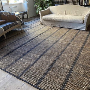 May include: A black and natural jute rug with a striped pattern. The rug has a woven texture and is made of natural fibers.