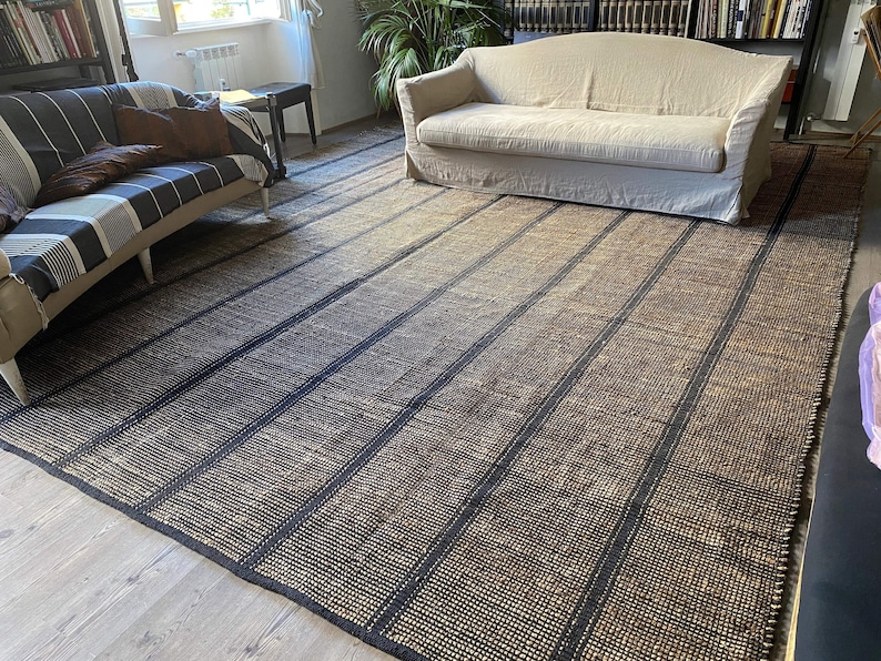 May include: A black and natural jute rug with a striped pattern. The rug has a woven texture and is made of natural fibers.