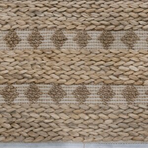 May include: A natural fiber rug with a woven pattern of brown and beige. The rug has a subtle diamond pattern in the center of the rug.