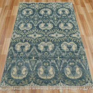 May include: A rectangular area rug with a detailed floral pattern in shades of blue, cream, and green. The rug has a fringe along the bottom edge and is placed on a wooden floor. The design features repeating floral motifs.