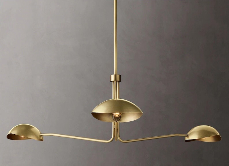 May include: A gold-toned three-light pendant light fixture with three round shades. The shades are angled and extend out from the center fixture.