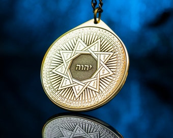 May include: A gold pendant necklace with a circular design featuring a six-pointed star with the Hebrew word "L'chaim" in the center. The pendant is surrounded by a circle of Hebrew letters and numbers.