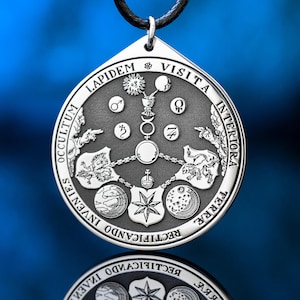 Könnte beinhalten: Silberfarbener Anhänger mit detaillierten himmlischen und alchemistischen Symbolen, darunter Planeten, Mondphasen und der Text "LAPIDEM VISITA INTERIORA TERRA OCCULTUM INVENIES RECTIFICANDO". Der Anhänger hängt an einem schwarzen Band.