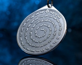 May include: Silver-toned pendant with a spiral design and Hebrew text. The pendant is teardrop-shaped and hangs from a black cord. The background is a blurred blue.