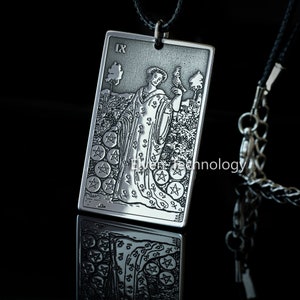 May include: A silver pendant necklace featuring a detailed etching of the 'The Star' tarot card. The card depicts a woman pouring water from two jars, with five stars above her head. The pendant is attached to a silver chain.