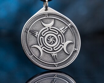 Puede incluir: Collar con colgante de plata con un diseño circular que presenta una espiral y tres lunas crecientes. El colgante está inscrito con las letras "H", "E", "X", "A", "V", "I", "T", "B" y "F".
