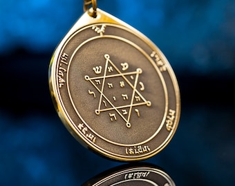 May include: A gold-colored pendant with a six-pointed star design and Hebrew lettering. The pendant is hanging from a chain and is reflected in a blue surface.
