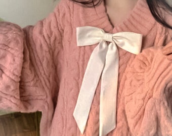 pink hand-knitted sweater with white ribbons